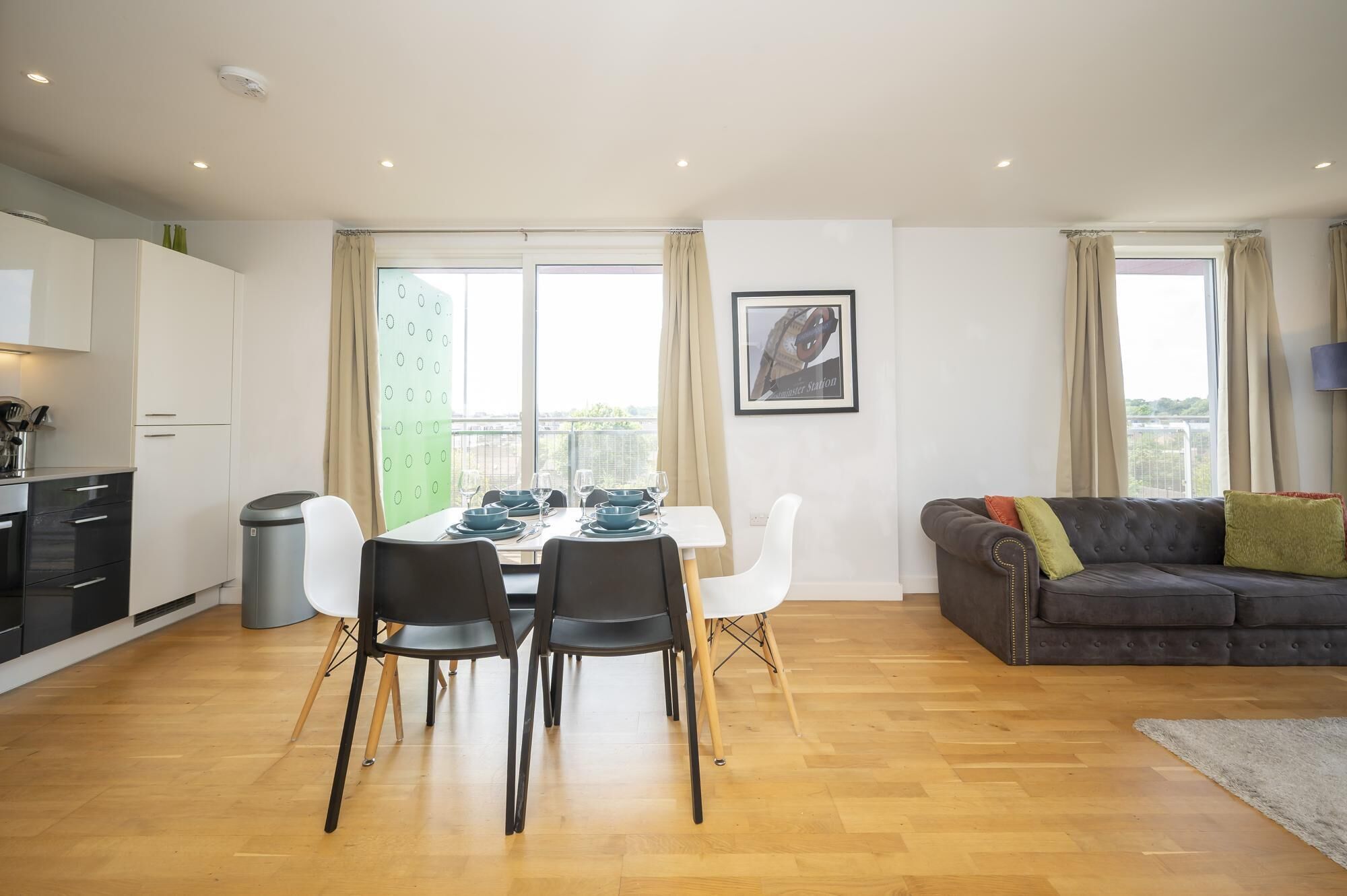 Ein modernes Wohnzimmer mit Essbereich, einem grauen Sofa und einem gerahmten Bild an der Wand.