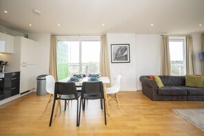 Ein modernes Wohnzimmer mit Essbereich, einem grauen Sofa und einem gerahmten Bild an der Wand.