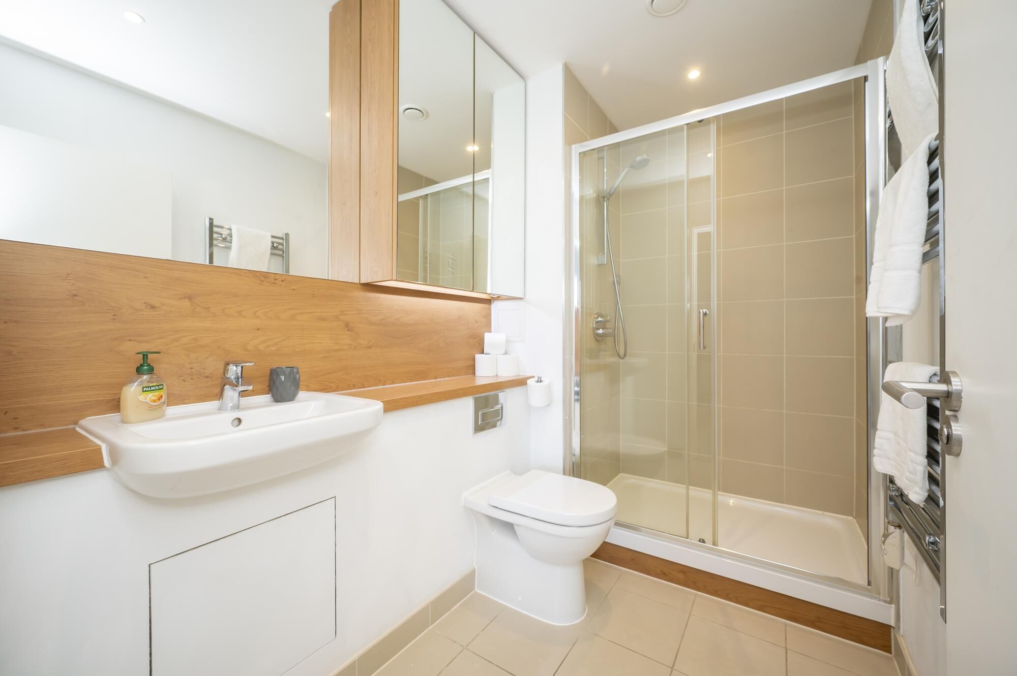 A modern bathroom with a sink, toilet, and glass-enclosed shower.