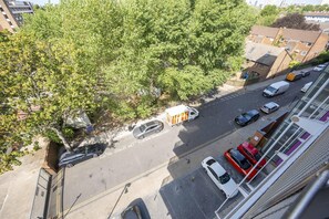 Vista callejera con automóviles estacionados, una furgoneta blanca y un edificio con fachada de ladrillo.