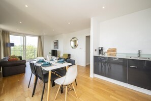 A modern kitchen with a dining area, a sofa, and a large window. - Comfortable 2BR apartment Deptford Yard, SE8 London - Pass the Keys (London)