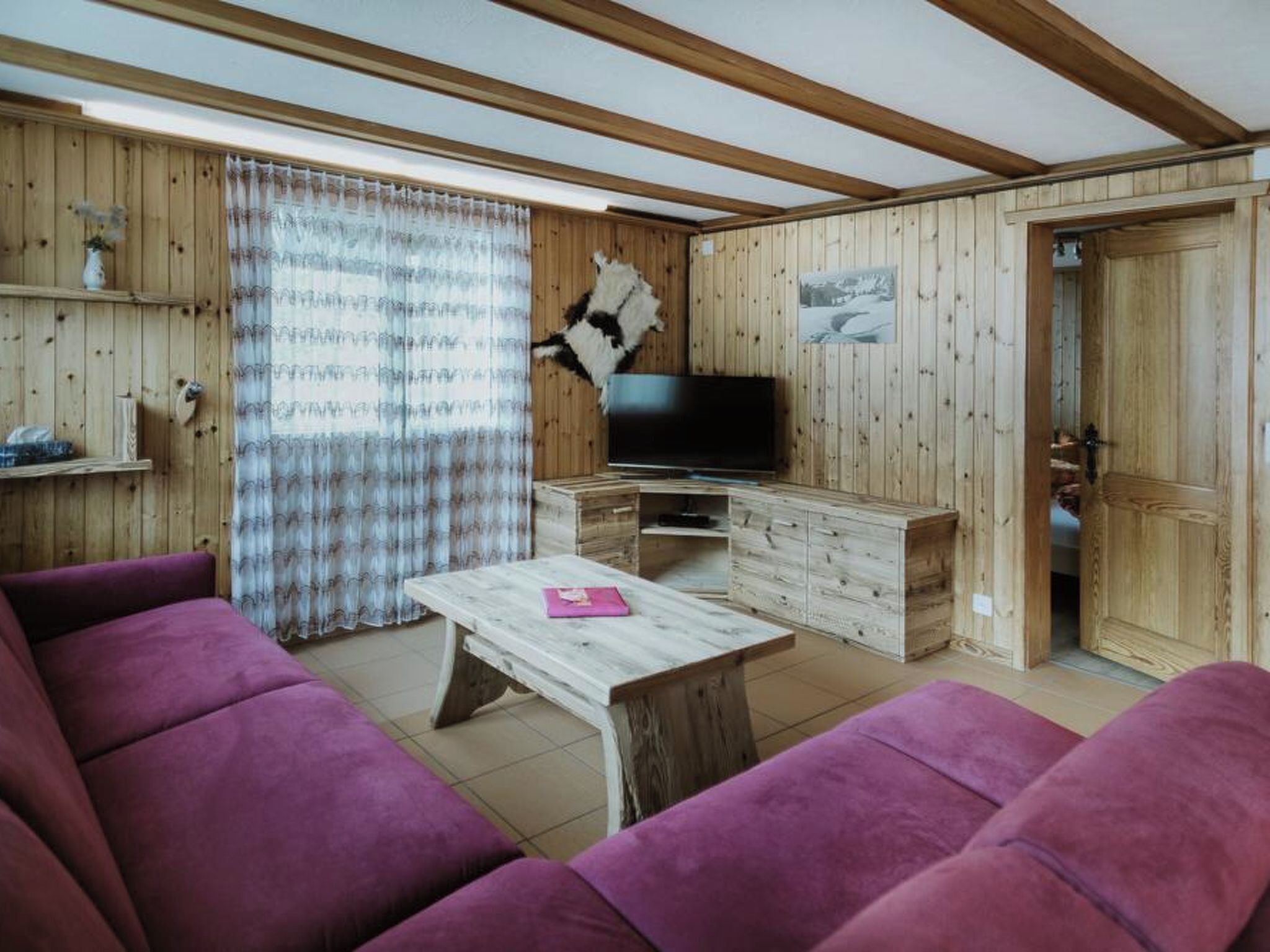 Een kamer met houten inrichting, een televisie, een bank en een tafel.