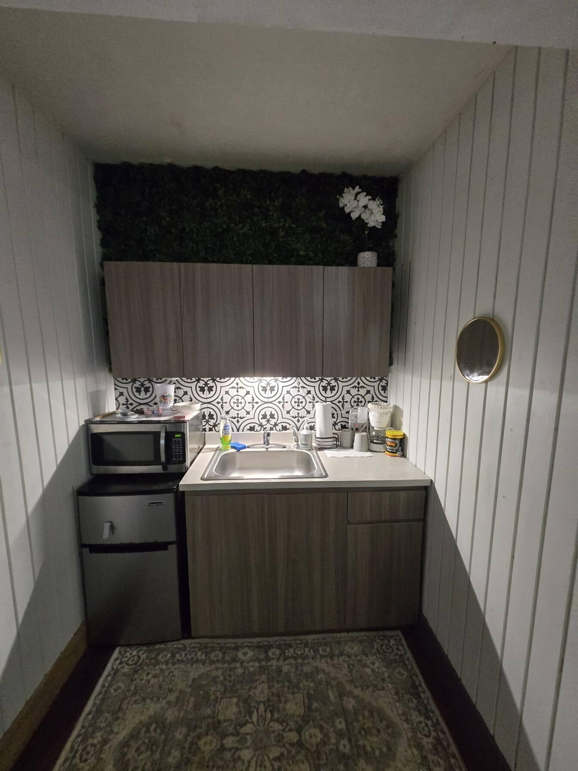 A compact kitchen with a microwave, sink, and small refrigerator.
