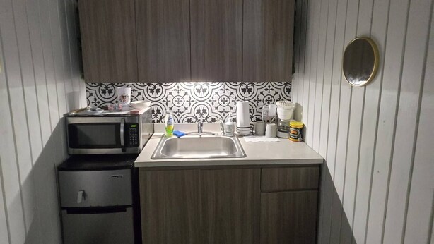 A compact kitchen with a microwave, sink, and small refrigerator. - Beach House Vega Alta PR (Sabana)