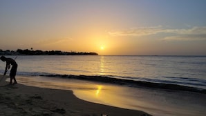 A beach scene with a person sweeping the sand. - Beach House Vega Alta PR (Sabana)