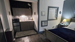 A compact room with a kitchenette, a bed, and a ceiling fan. - Beach House Vega Alta PR (Sabana)