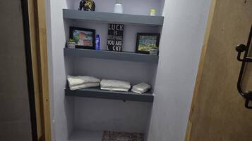 A narrow hallway with a small bathroom area, including a shelf with toiletries and a motivational sign.