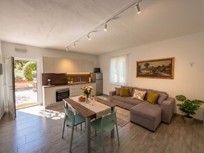A modern living space with a dining area, kitchen, and a large window. - Casa Melape Garden & Solarium (Tremosine)