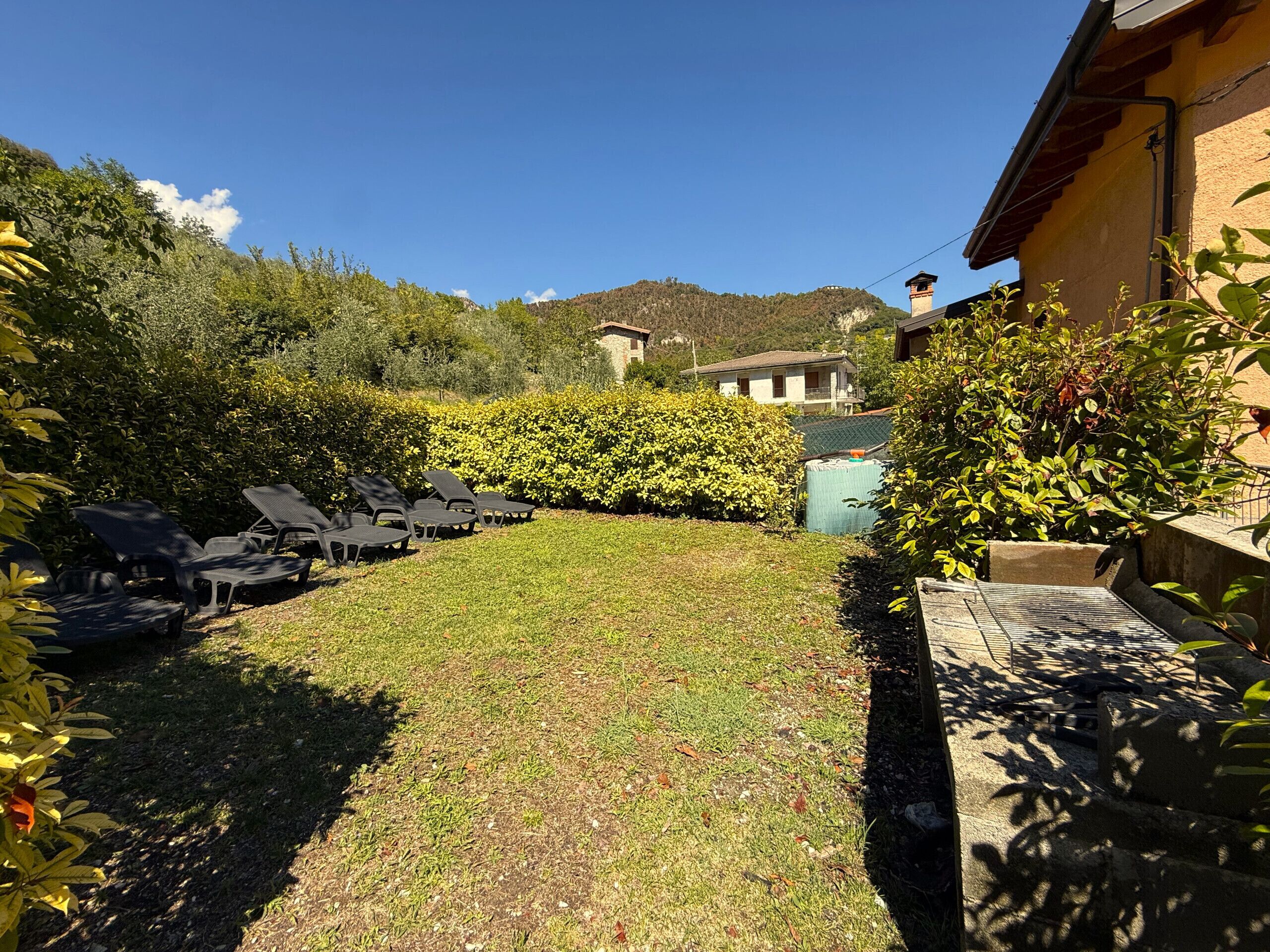A garden with sun loungers, a water tank, and a building in the background.