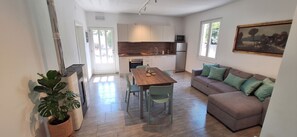 A modern kitchen with a dining area, a sofa, and a potted plant. - Casa Melape Garden & Solarium (Tremosine)