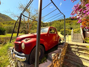 A vintage red car parked in a stone-walled area with a staircase leading to a building with pink flowers. - Casa Melape Garden & Solarium (Tremosine)