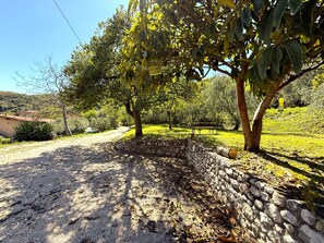 A stone wall with a gravel path leading to a bench under trees. - Casa Melape Garden & Solarium (Tremosine)