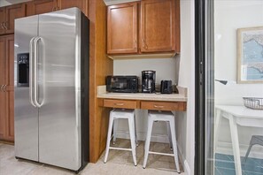 A compact kitchen with a stainless steel refrigerator, wooden cabinets, a microwave, and a coffee maker. - Private Patio, 2 Masters, Near Beach, Mayo & TPC (Ponte)