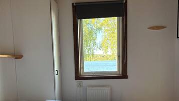 A bedroom with a bed, a window with a view of trees, and a radiator.