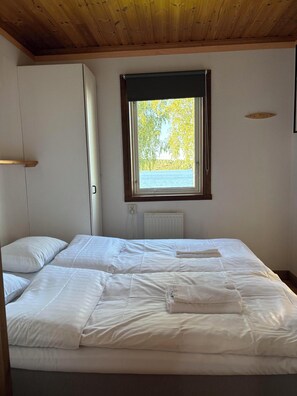 A bedroom with a bed, a window with a view of trees, and a radiator.
