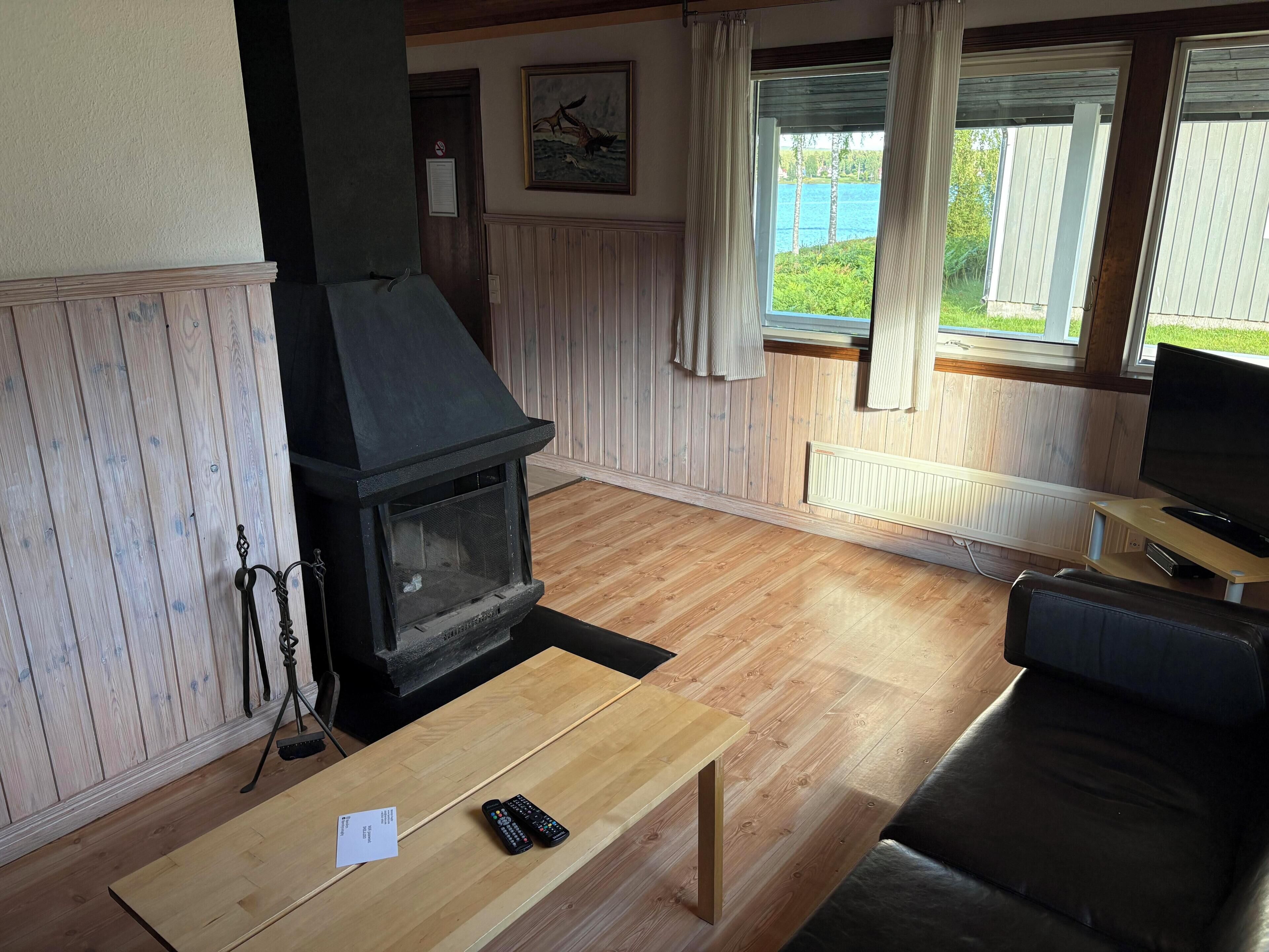 Ein Wohnzimmer mit Kaminofen, Fernseher und Seeblick.