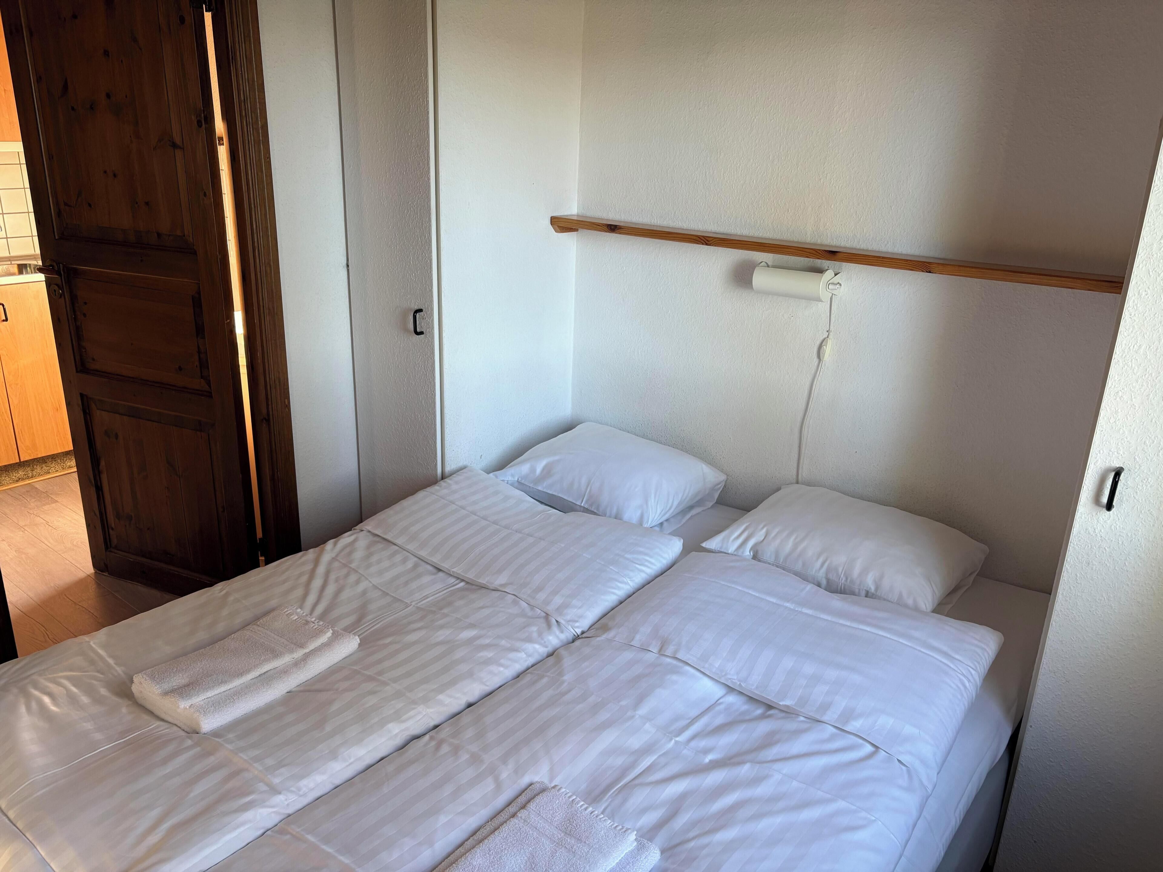 A single bed with white bedding and a wooden headboard.