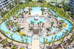 A large, circular swimming pool with multiple lanes, surrounded by palm trees and sun loungers. - Beautiful Beachside Studio DW V504 (Fort Walton Beach)