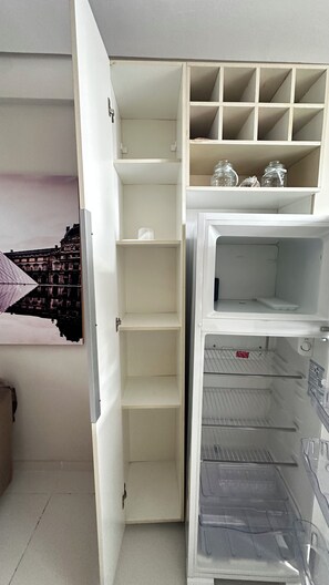 A partially open refrigerator with shelves and a freezer compartment. - 305 2 Qtos - 15 min Centro (Belém)