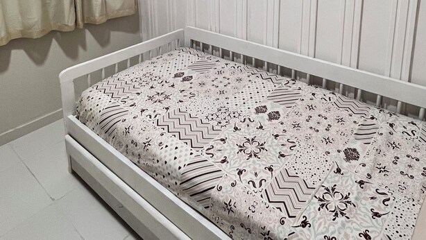 Ein Schlafzimmer mit einem Bett, einem Wandbild und einem Fenster mit Vorhängen.