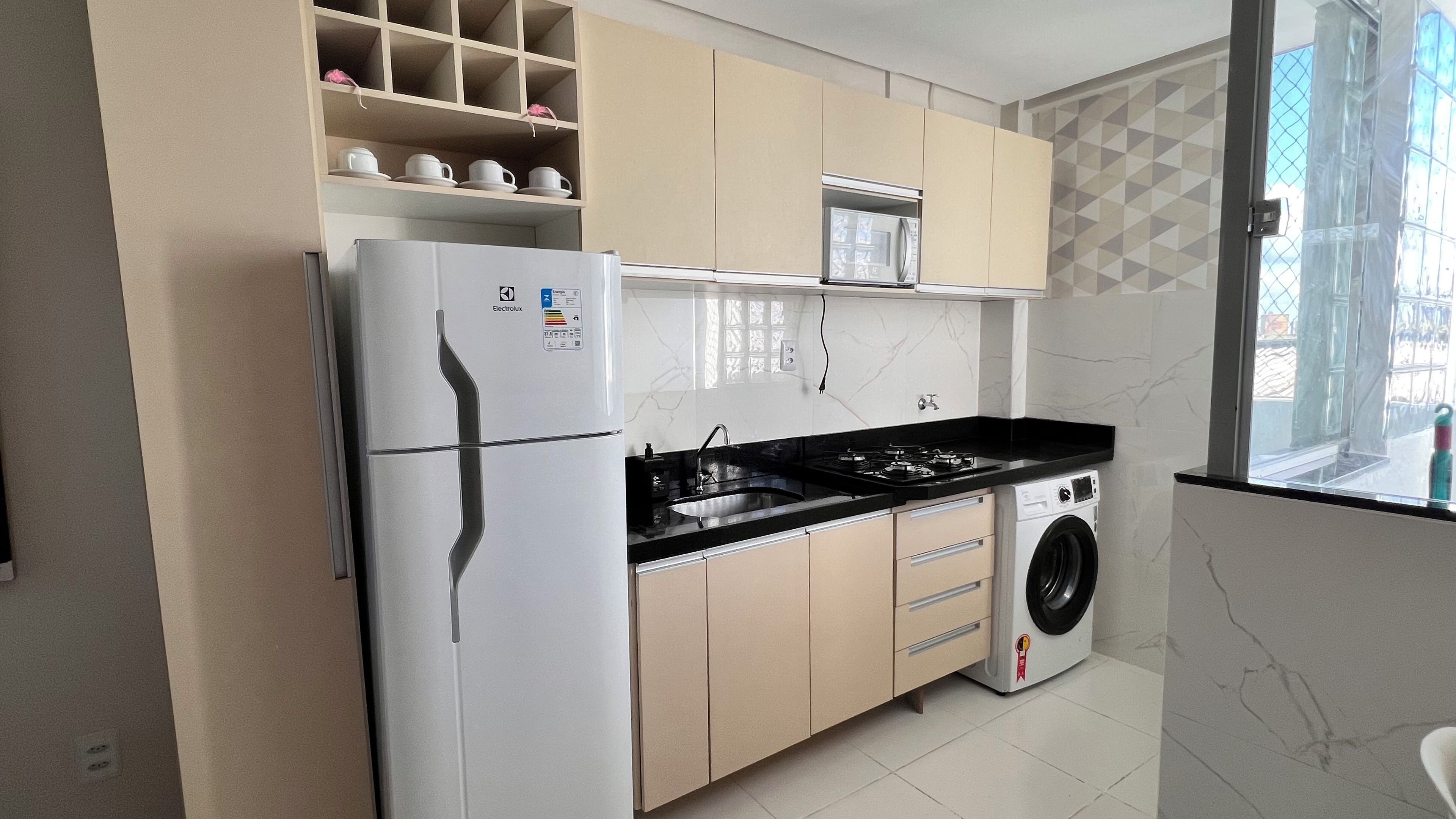 Una cocina funcional con refrigerador, microondas, estufa y lavadora.