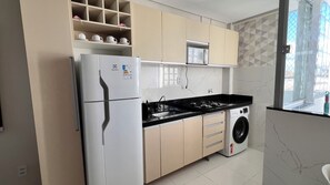 A compact kitchen with a refrigerator, microwave, stove, and washing machine. - 305 2 Qtos - 15 min Centro (Belém)