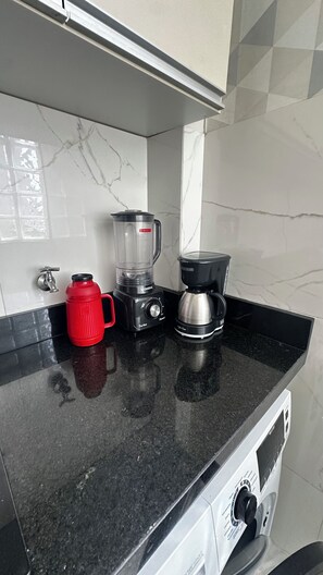 A kitchen counter with a blender, a coffee maker, and a red water jug. - 305 2 Qtos - 15 min Centro (Belém)
