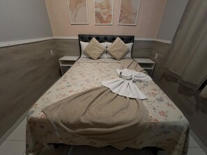 A neatly made bed with a floral bedspread, two pillows, and a towel. - 305 2 Qtos - 15 min Centro (Belém)