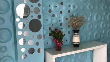 Zona de recepción con pared azul con textura, una mesa consola blanca y una lámpara colgante.