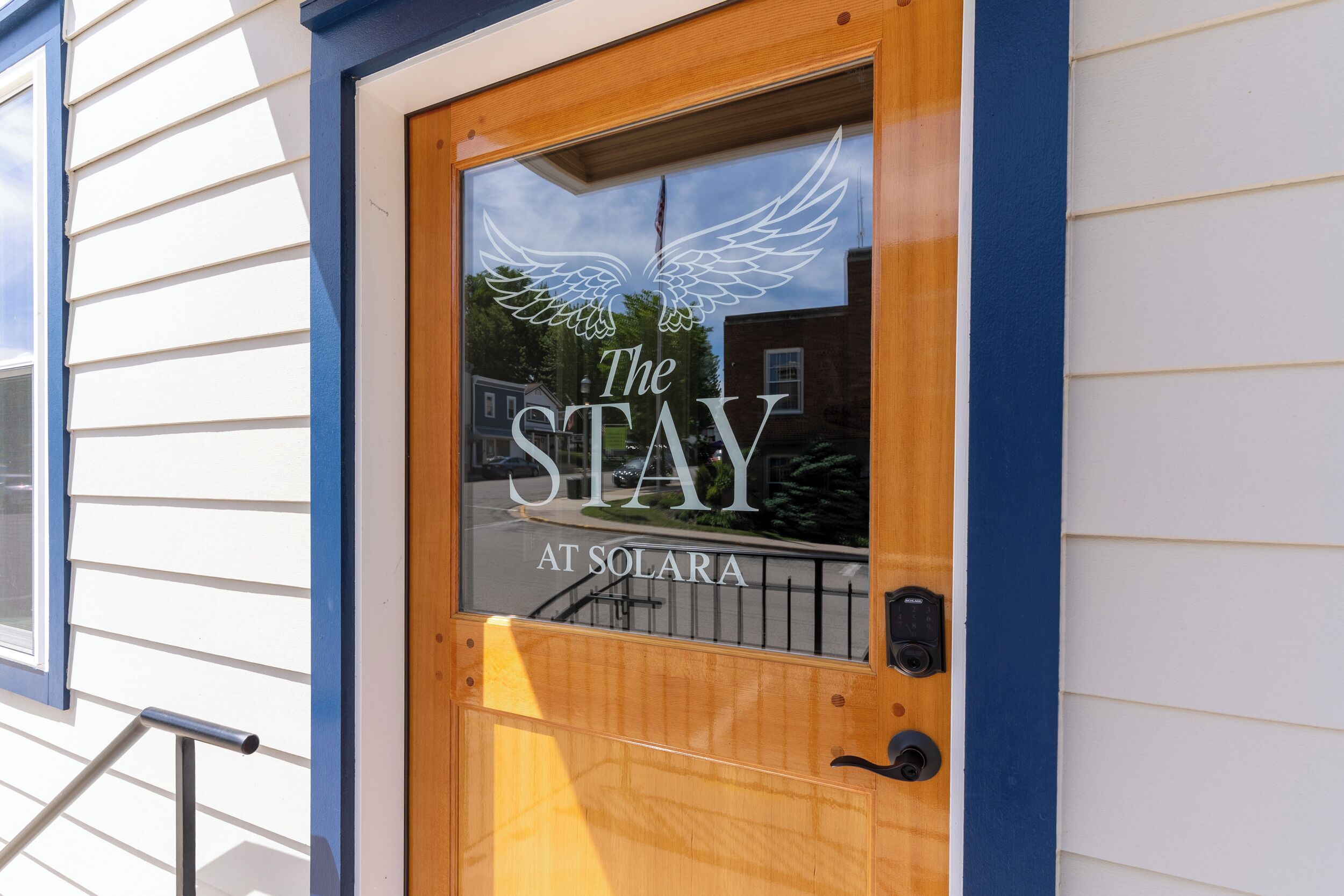 Une porte en bois avec un vitrage orné d’un logo représentant des ailes et de l’inscription « The Stay at Solara ».