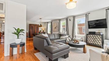 A modern living room with a sectional sofa, a dining area with a pool table, and a kitchen in the background.