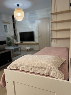 Ein Schlafzimmer mit einem Bett, einem Fernseher, einem Kleiderschrank und einer Pendelleuchte.