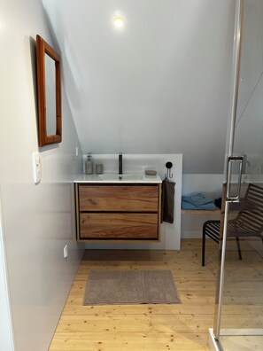 A modern bathroom with a wooden vanity, a mirror, a sink, and a towel rack. - A small house in a private courtyard in the heart of Pont-Aven, across from the museum (Pont-Aven)