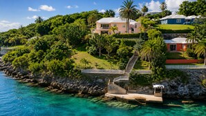 A coastal property with a clear view of the ocean, a staircase leading to the main building, and lush greenery. - Private Dock - Sunset Ocean Views - Sleeps 9 - 3 Kings - 5 Min Walk to Beach (Southampton)