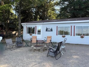 A cabin with a fire pit, outdoor seating, and a view of the forest.
