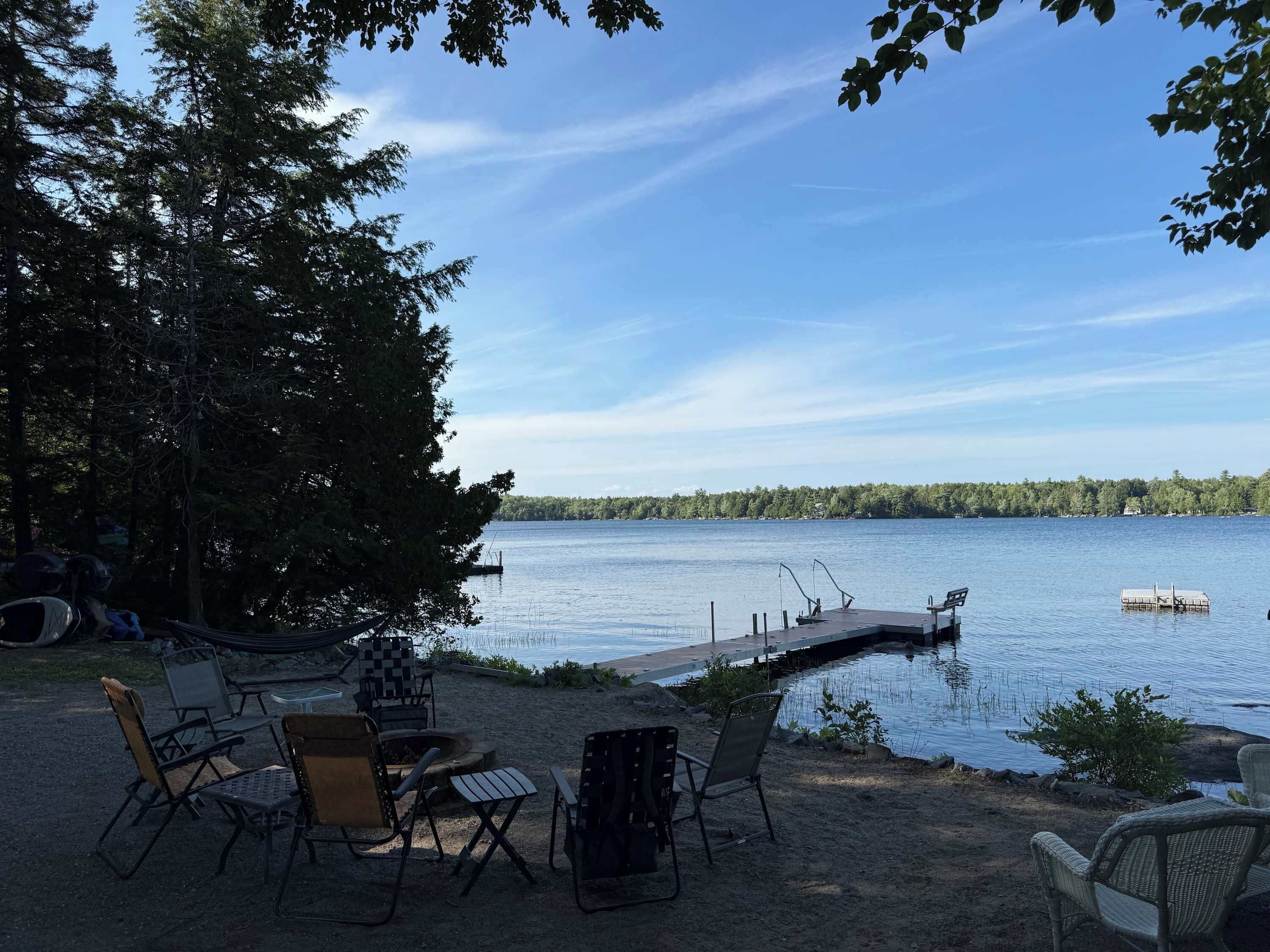 A lakeside deck with outdoor seating and a dock extending into the water.