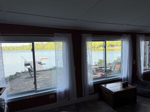 A room with large windows overlooking a lake, a wooden bench, and a small table.