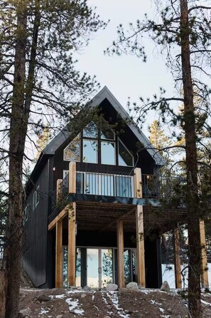 A modern cabin with a balcony, surrounded by trees, and a view of the landscape. - Work/Play Retreat: 1BR Modern Alpine Cabin Residence w/ HotTub (Twin Lakes)