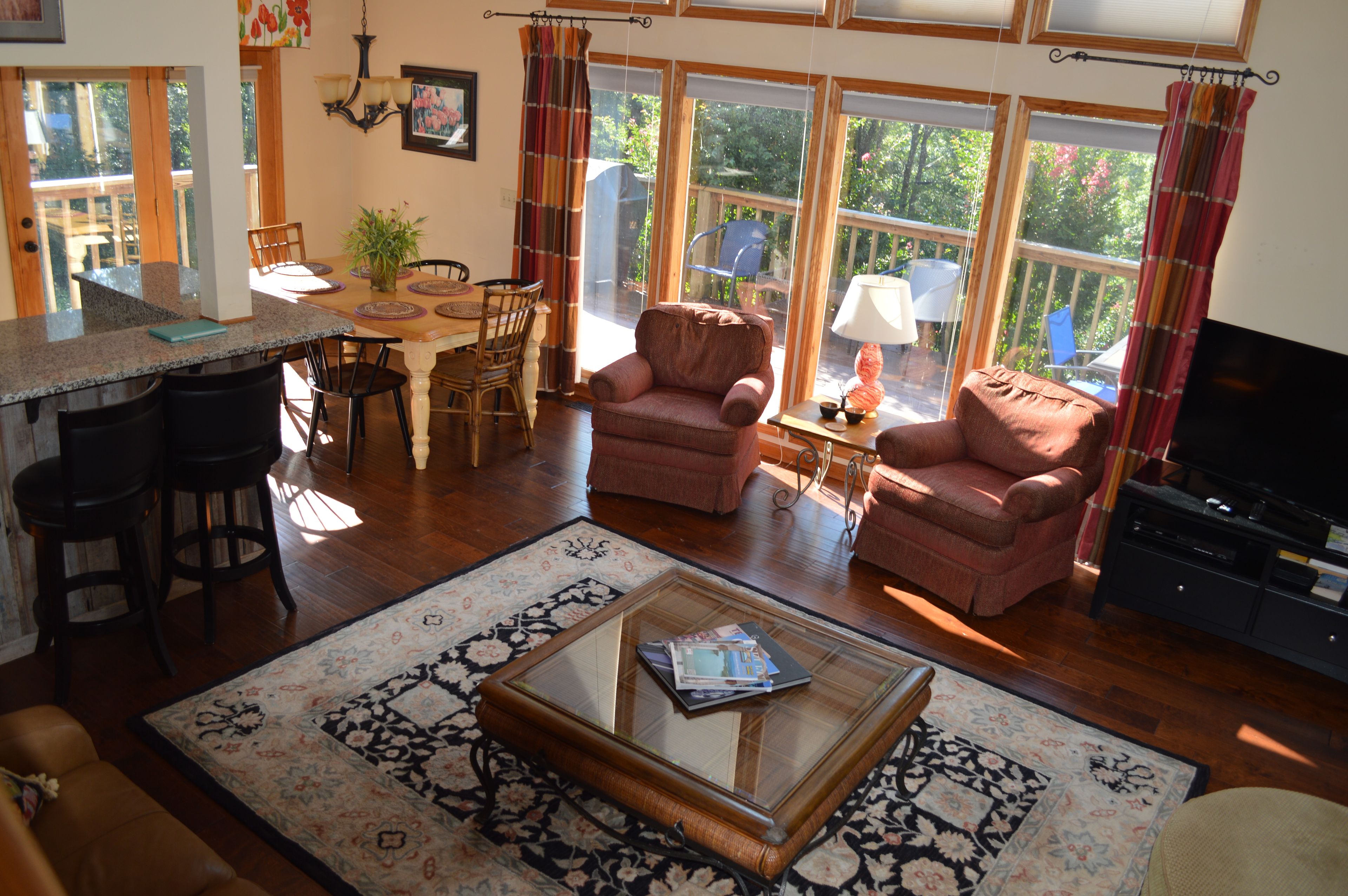 A spacious living room with a dining area, large windows, and a television.