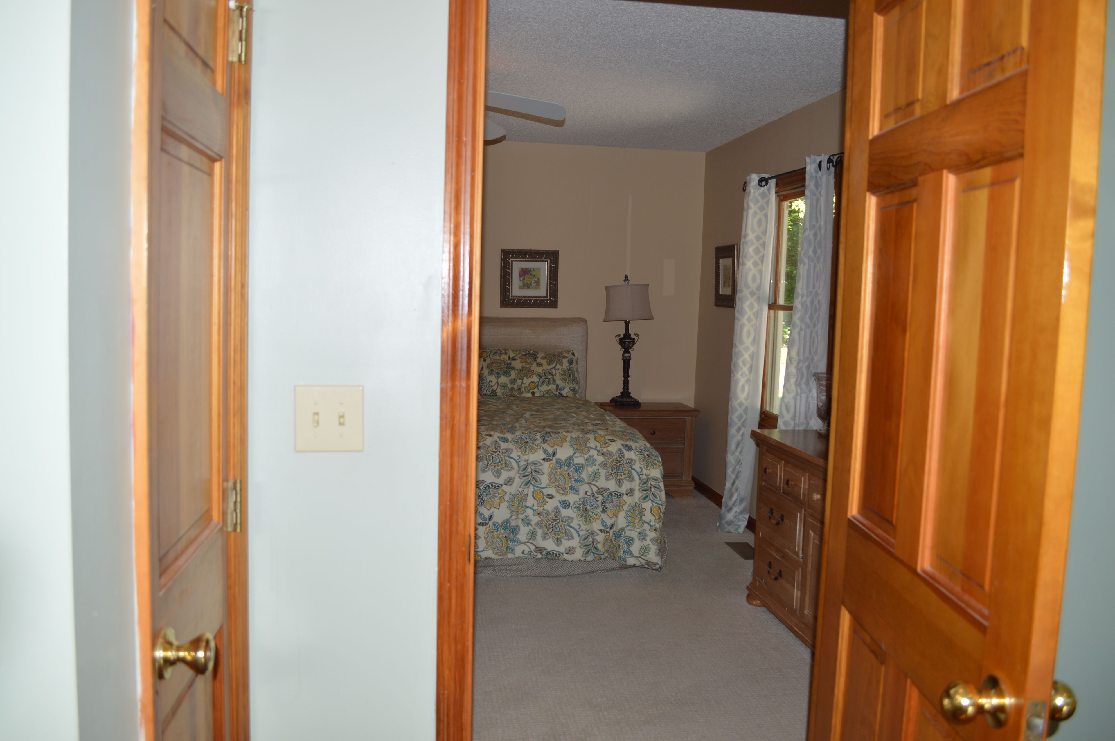 A bedroom with a bed, a nightstand, a lamp, and a dresser.