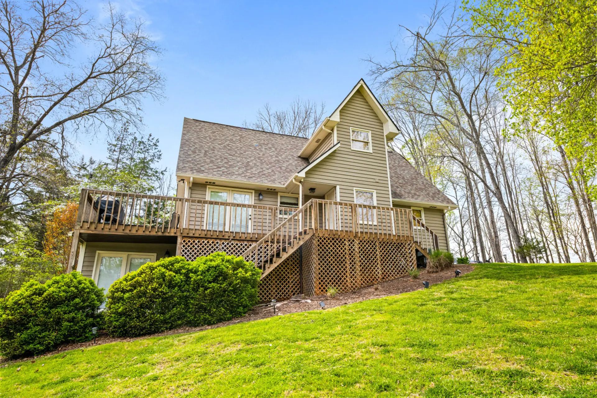 A two-story house with a front deck, a covered porch, and a small front yard.
