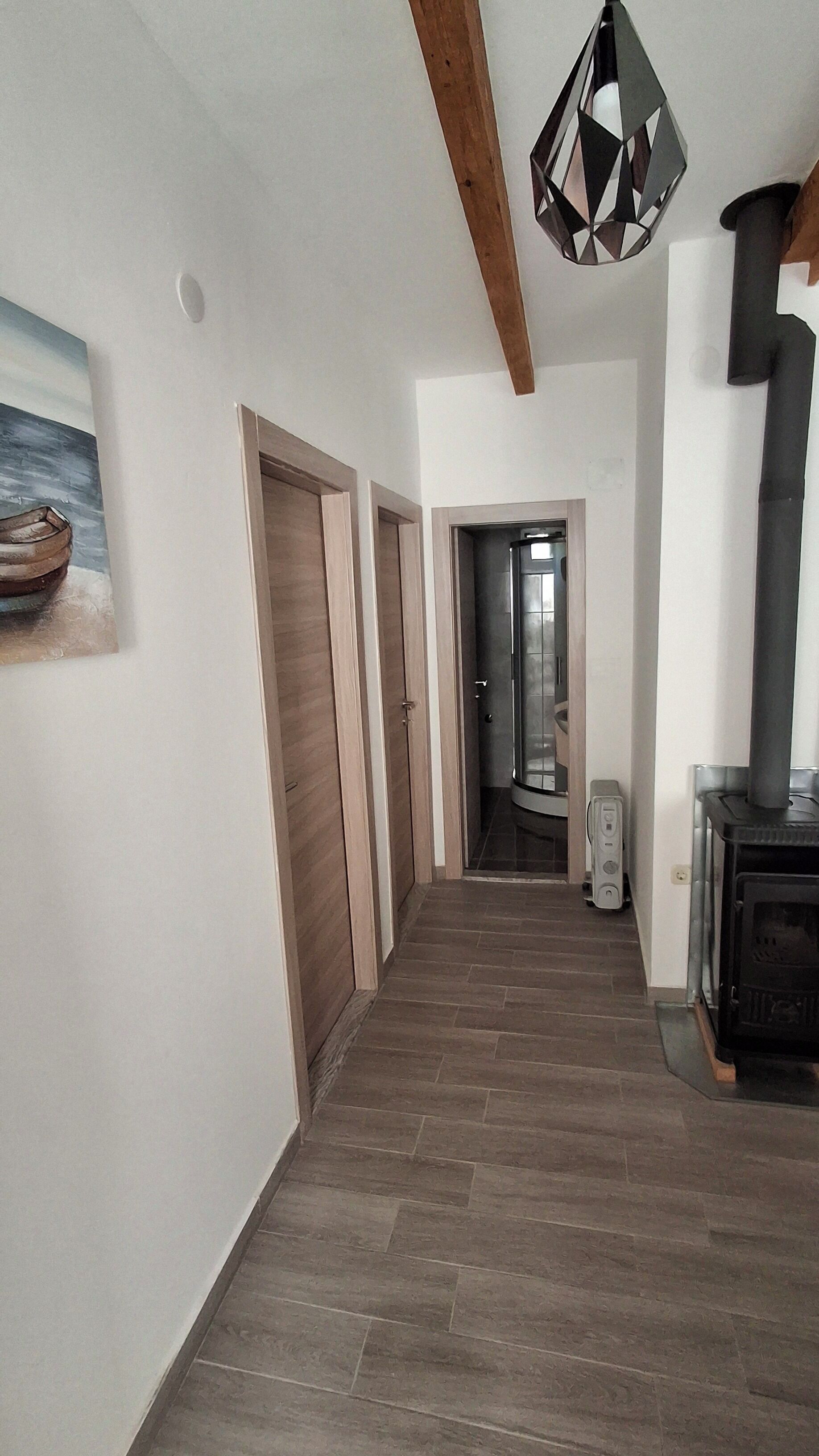 Ein Flur mit Holzboden, einem Gemälde an der Wand und einem schwarzen Herd rechts.