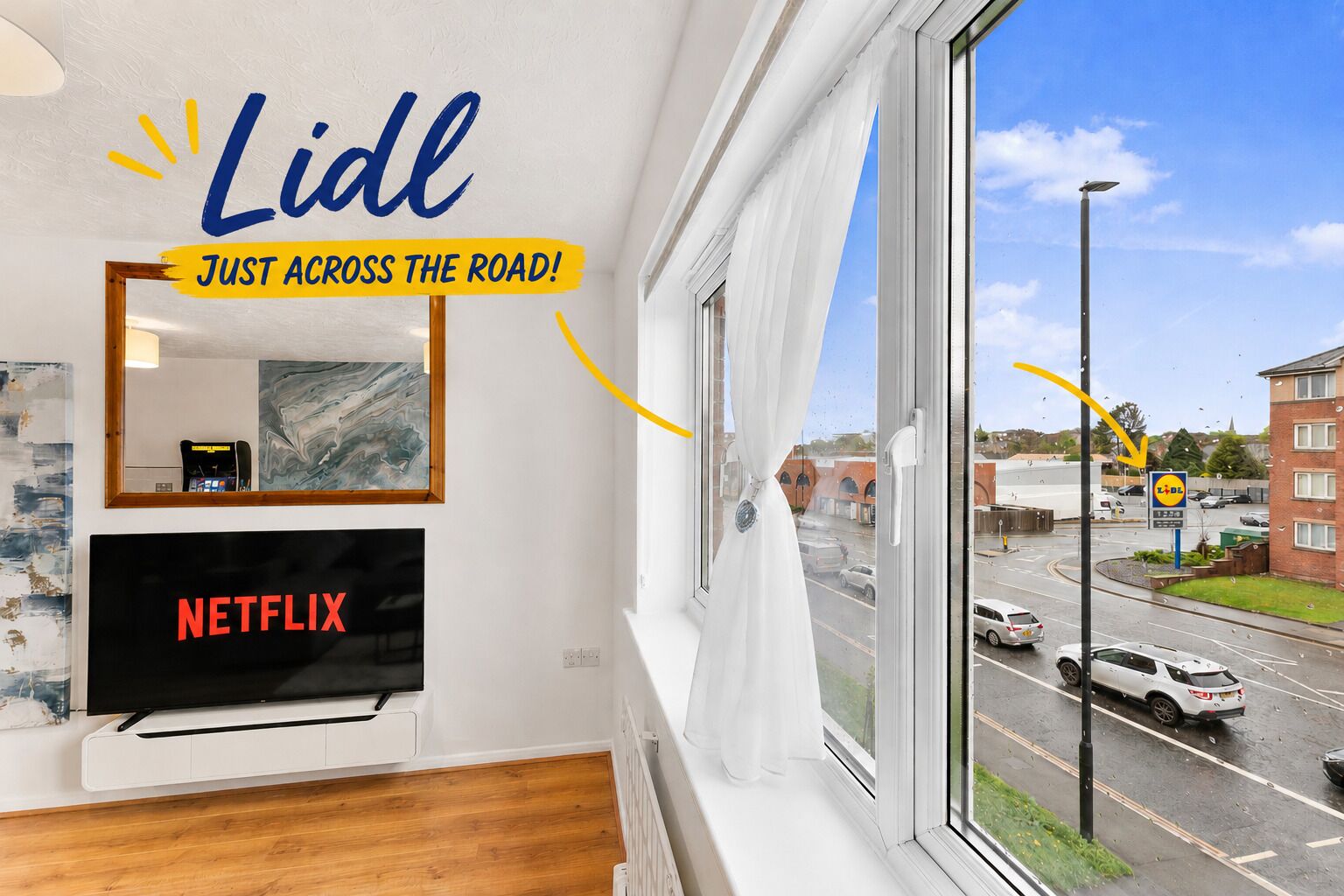 A room with a large window, a television, and a mirror.