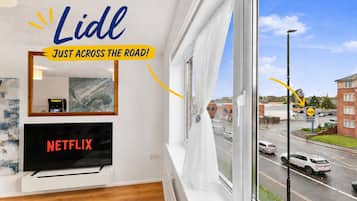 A room with a large window, a television, and a mirror.