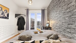 Habitación de hotel con una cama, una computadora portátil sobre una mesita de noche, una bandeja de desayuno y vistas al exterior.