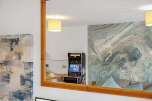 A room with a marble wall, a gaming console, and a mirror reflecting the room. - Central Derby 2-Bed | Arcade, Free Parking, King Bed & Ultrafast Wi-Fi (Derby)