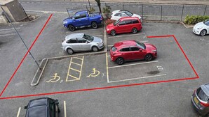 Un estacionamiento con espacios reservados para discapacitados y una línea divisoria roja.