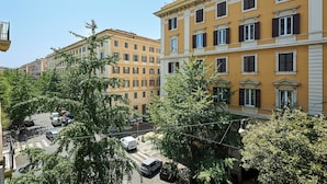 A street view with multi-story buildings, parked cars, and trees. - Prati Design Home (Roma)