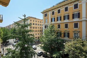 A street view with multi-story buildings, parked cars, and trees. - Prati Design Home (Roma)