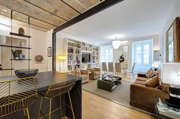A modern living room with a dining area, a bookshelf, and a television. - Prati Design Home (Roma)
